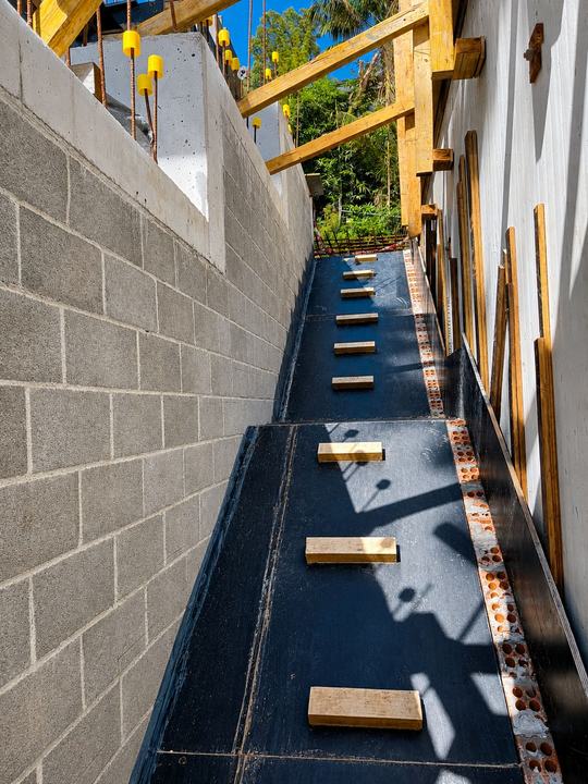 Barrier membrane detailed against a block retaining wall