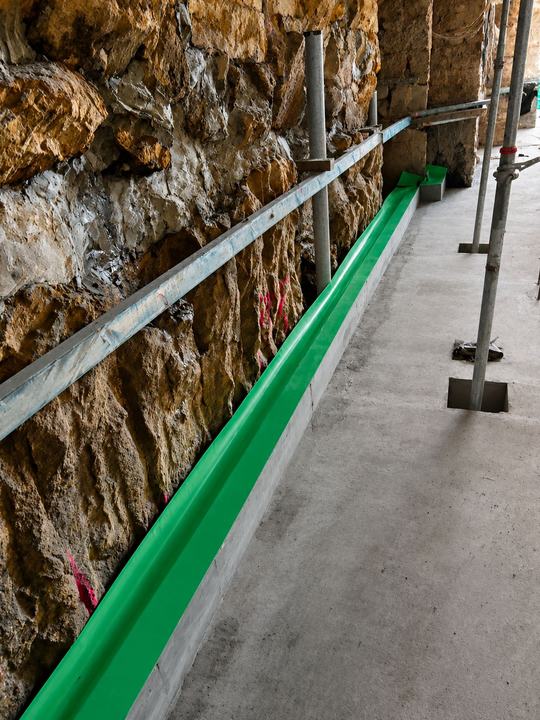 Perimeter barrier run against a sandstone wall