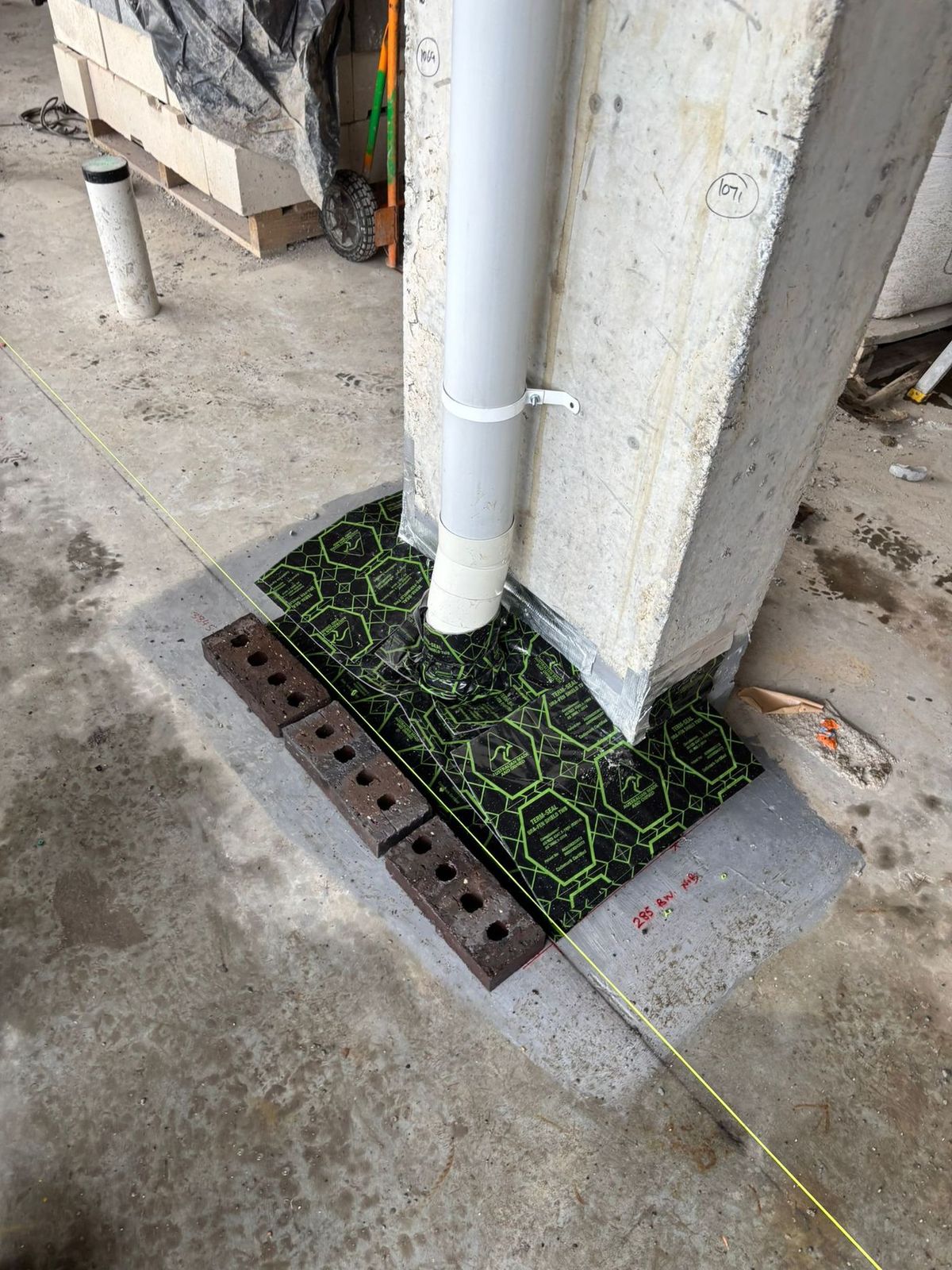 Barrier membrane sealed around a service pipe at a column
